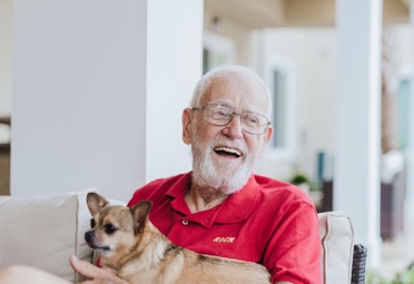 Senior man seated with a small dog on his lap